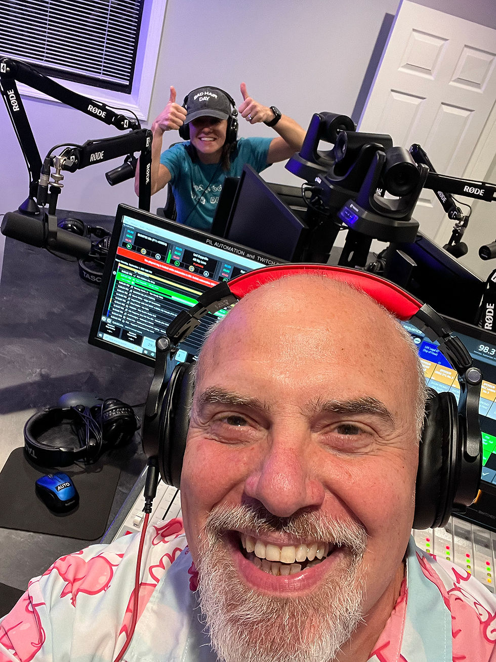 Marty Jalove, Master Happiness and Agnieszka of TOTS in a radio studio, both wearing headphones. One gives thumbs up. Bright colors, screens, and equipment in the background, creating a lively mood.