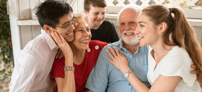 Vrolijke multigenerationele familie lachend, knuffelend en samen genietend op veranda.