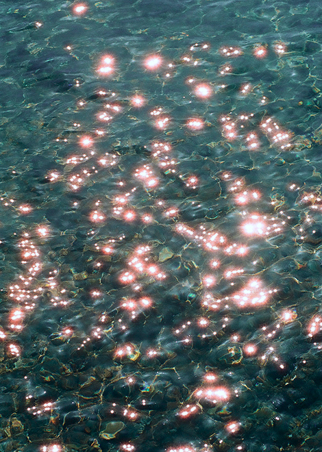 The image shows dark ripples on water. The water reflects light creating light and dark patches.
