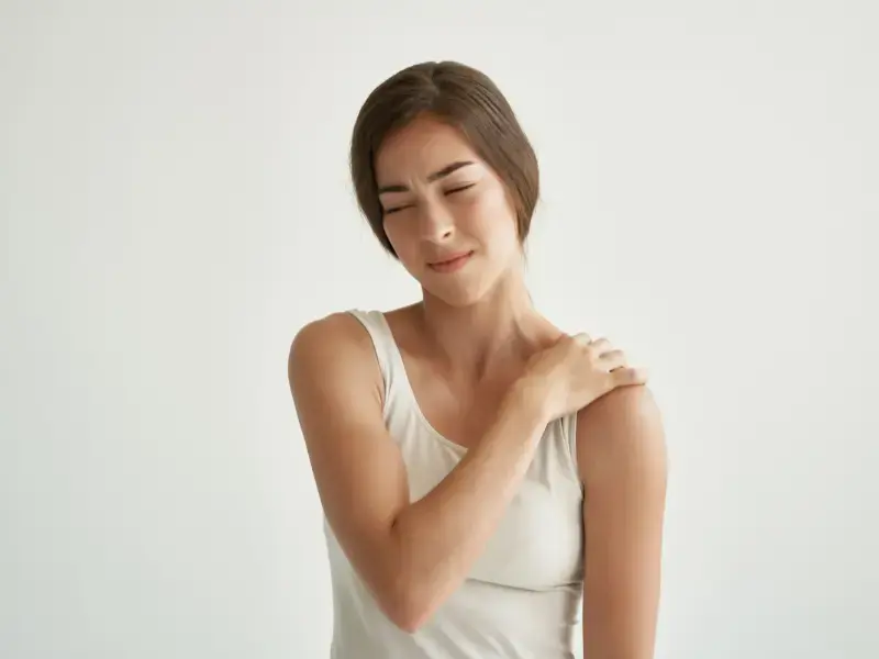 donna con espressione di dolore che si tocca la spalla