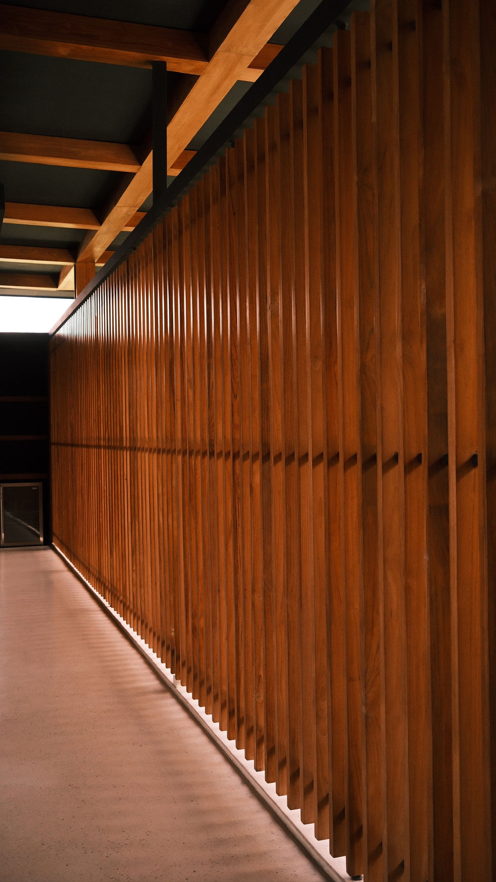 Modern architectural wooden walkway with dramatic light and shadows at the effortlessly refined Magna Pacific villa.