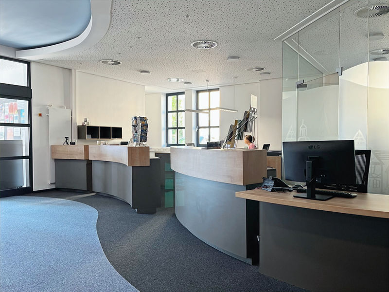 Modernisierung und Umgestaltung des ehemaligen Postgebäudes zum Tourismuscenter. Geschwungene Empfangstresen aus geformter Unterkonstruktion mit HPL beschichtet. Arbeitsplätze wurden mit Schubkästen und offenen Fächern ausgestattet.