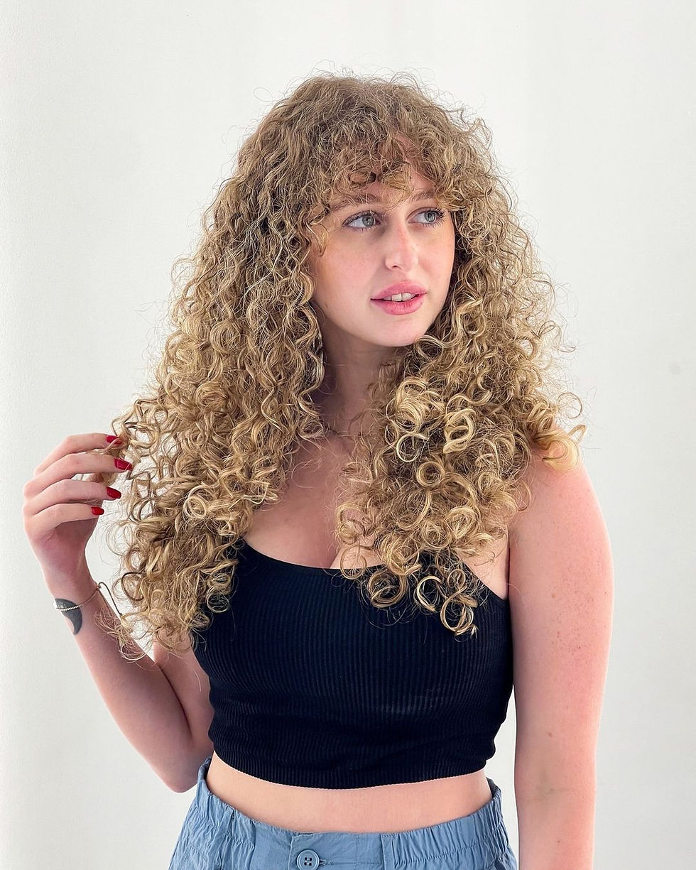 Woman with long golden blonde curly hair styled with volume and definition