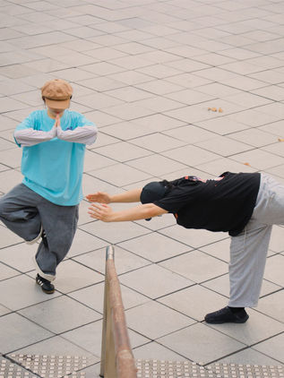 Two dancers mid-pose on a tiled floor in MUTE x LOVEURJAM tees