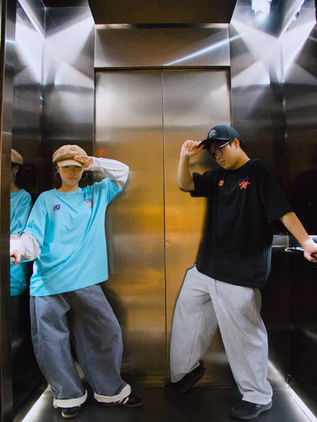 Two dancers posing in a lift wearing the MUTE x LOVEURJAM tee in mint blue and black
