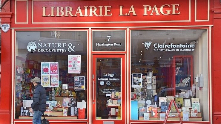 Image of the front of Librarie La Page bookshop. The front is painted red and brightly coloured books are displayed in the window
