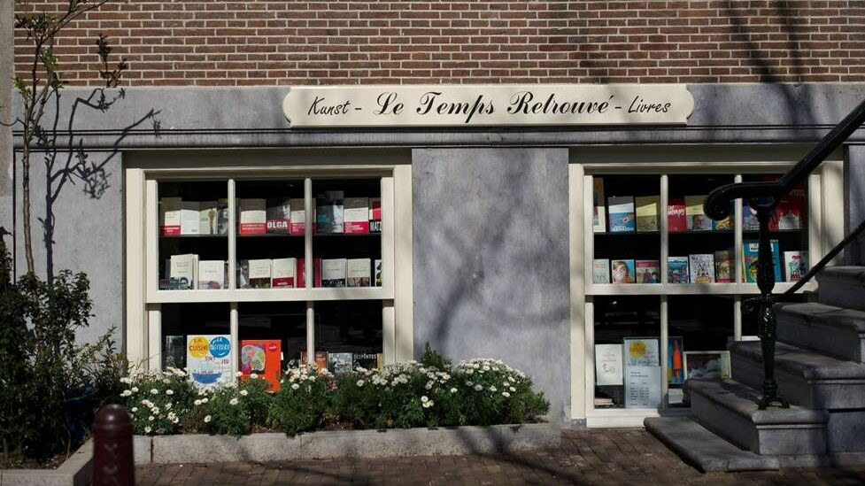 Image of the windows of Le Temps Retrouvé bookshop. A grey shop with books displayed in the window.