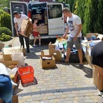 Люди розвантажують коробки з гуманітарною допомогою біля бусу. Фото звіт - Соціальні проєкти.