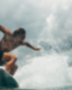 Surfer riding a wave, splashing water. The sky is cloudy. The mood is intense and dynamic, capturing action and energy.
