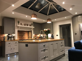 Restoration shows internal house with kitchen with island and wood worktops, stone floor lit at night