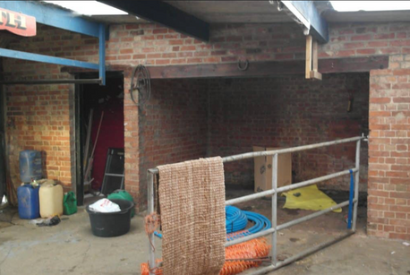 Shows red brick farmhouse yard before restoration