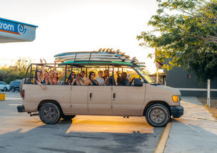 marea surf school truck with surfers and boards on top during sunset