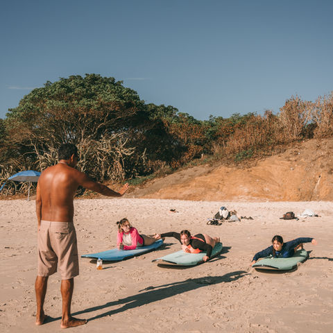 Three people taking a surf class