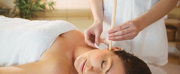 Young woman getting an ear candling treatment in therapy room.jpg