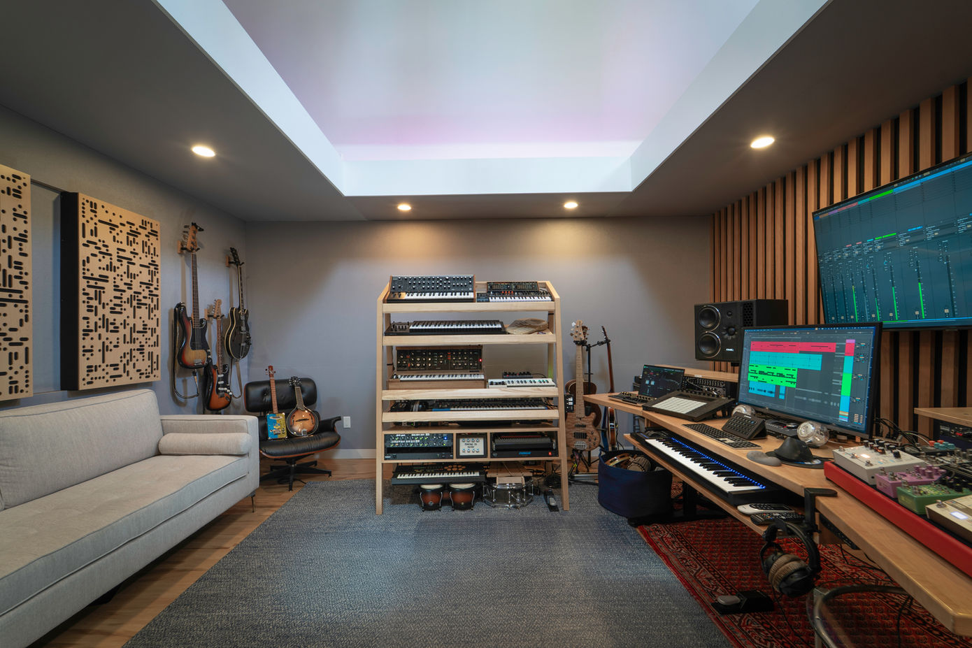Home music studio with synthesizers, guitars, and monitors.