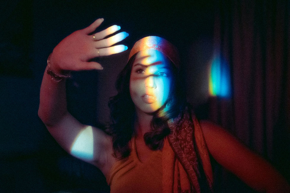Woman with raised hand, rainbow light on face