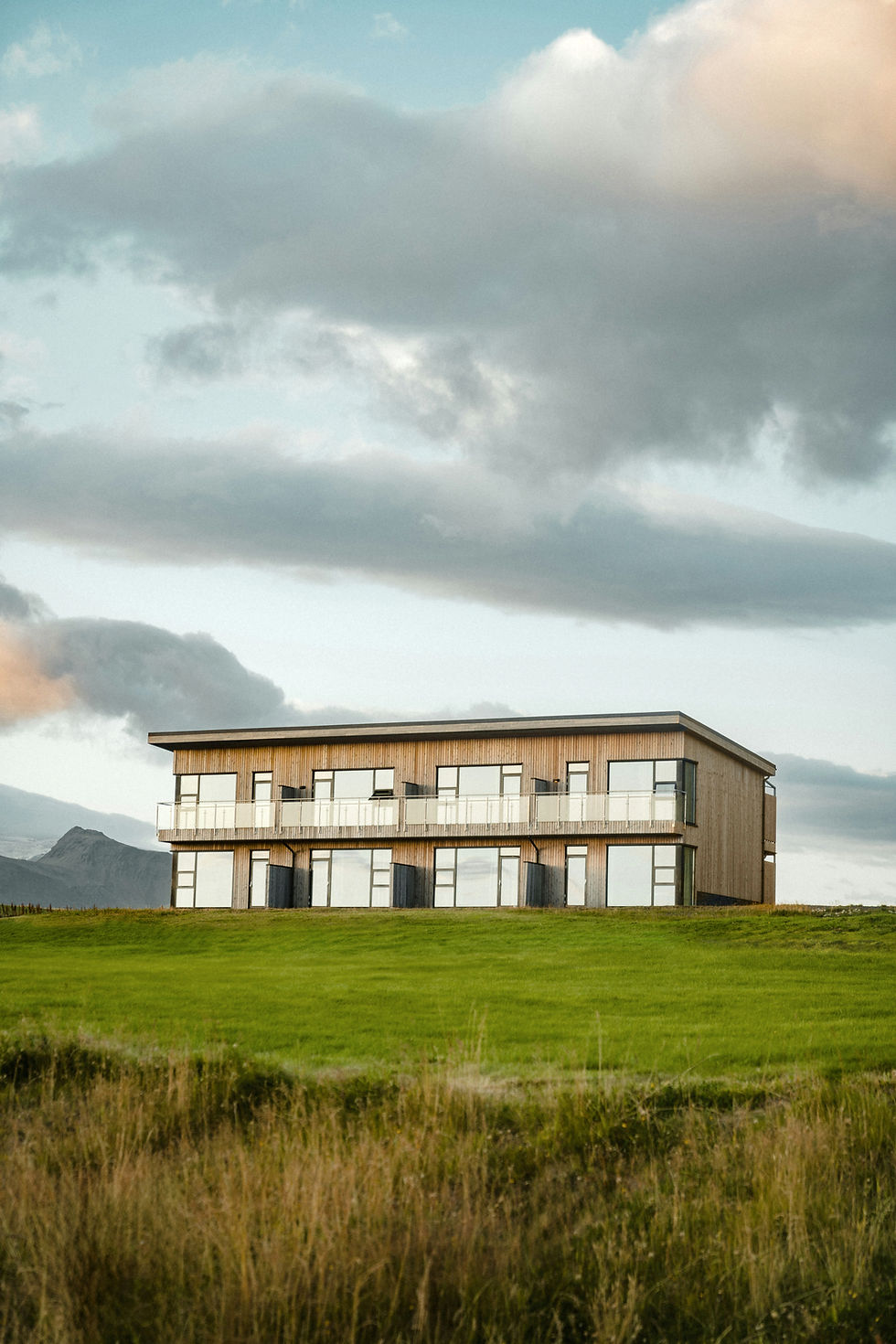 Modern two-story building on a grassy hill under a cloudy sky.