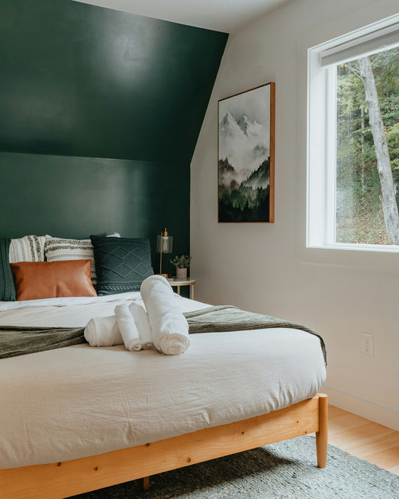 Cozy bedroom with green accent wall, bed, and framed mountain art My Site 8