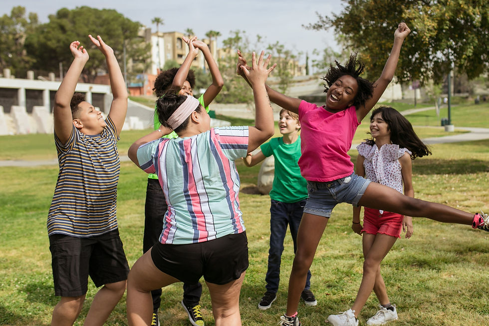 Lachende kinderen die buiten in een park dansen en juichen.