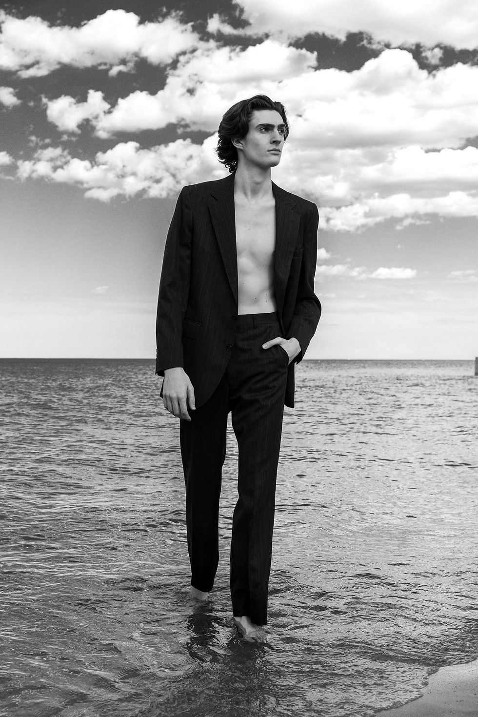Man walking in ocean wearing a suit jacket