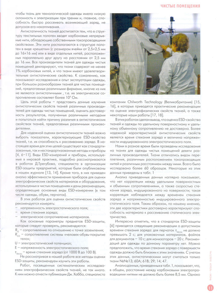 Два работника в белой одежде для чистых помещений работают с оборудованием.