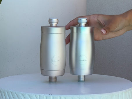 2 x Shower Filters (1 x Rose Gold and 1 x Chrome), on a white table. A hand is reaching out to pick their favourite colour.