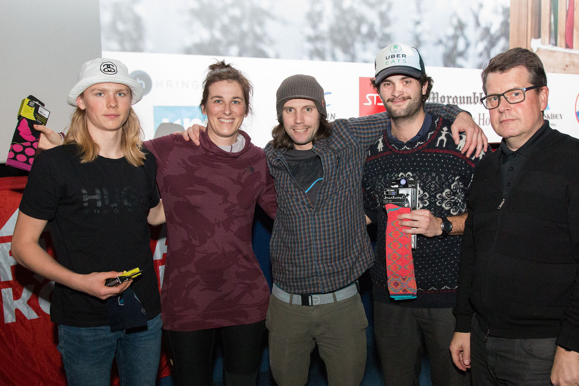A group of five people holding prizes in front of a big screen
