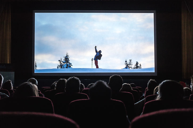 Audience in a movie theater watching a film on a big screen