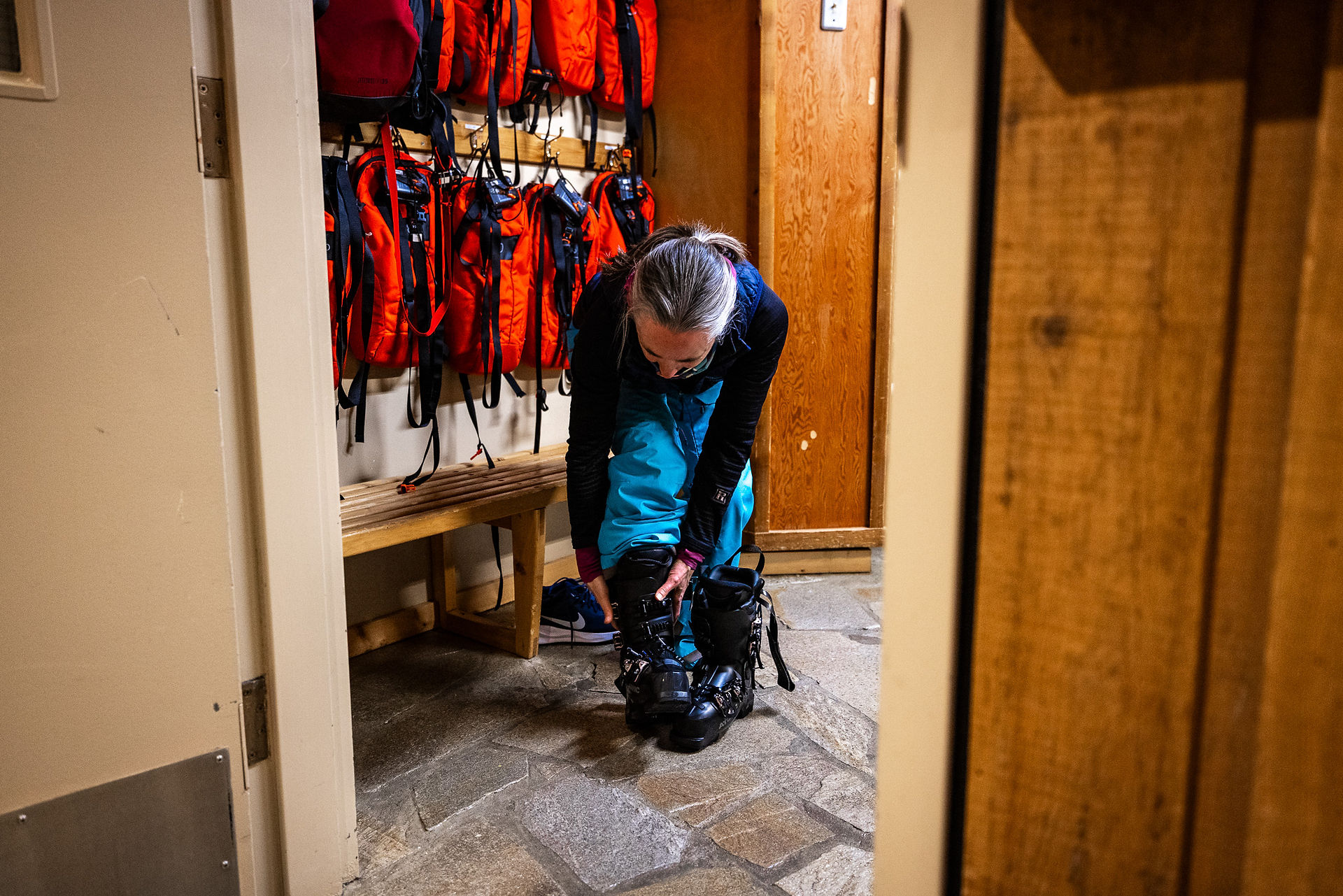 A woman putting on her ski boots in a locker room