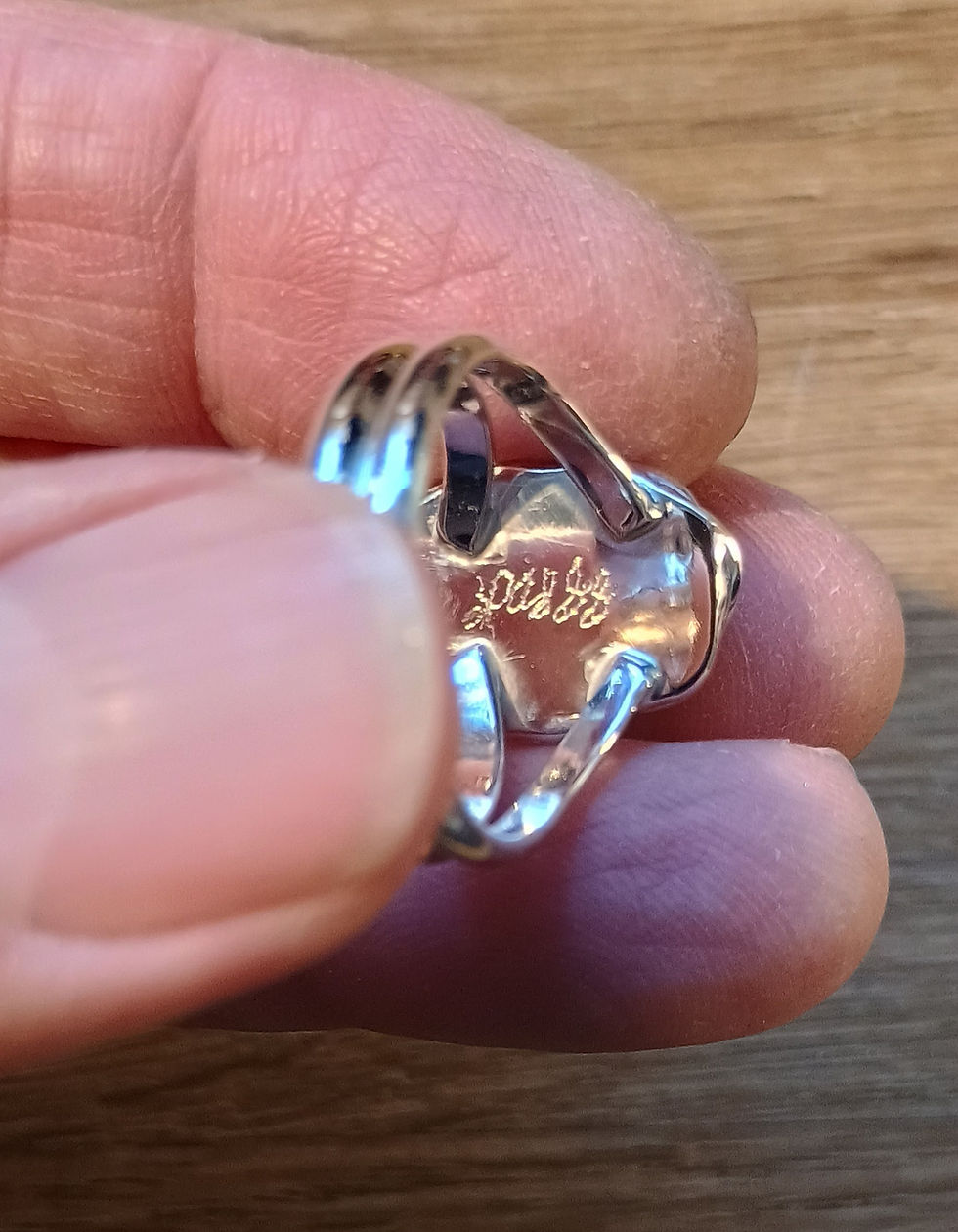 Polished reverse side of a silver ring setting showing the double split shank connection and stamped maker hallmark.