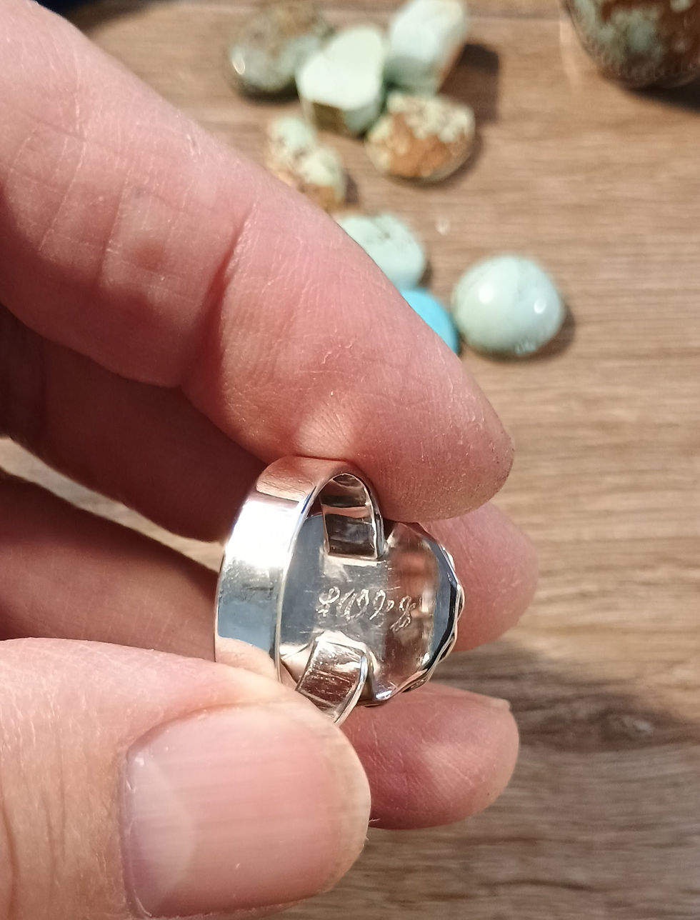 Thumbnail: Inside backplate of a sterling silver ring displaying a wide flat shank and the hand-engraved artisan maker signature.