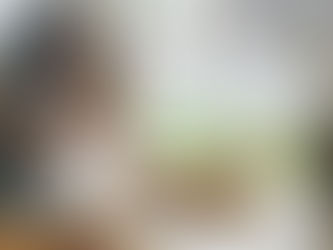 A young woman sits at a window reading with her dog and a cup of tea on the sidetable.