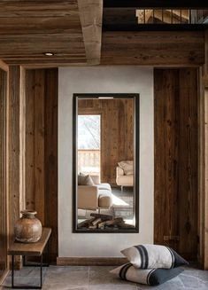 Décoration intérieure d'un chalet avec grand miroir qui reflète l'extérieur