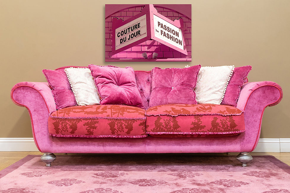 Pink velvet sofa with floral cushions against a beige wall. Above, a pink movie marquee wall art design reads "Couture Du Jour" and "Passion for Fashion."