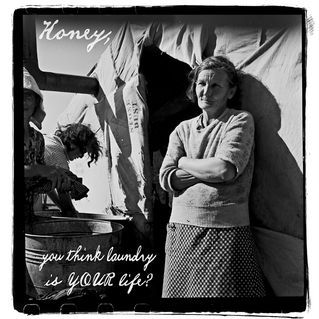 Vintage black and white photograph of a woman standing outside a tent and another woman using a washboard to wash her clothing.