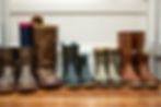 Boots lined up on an LVP floor, featuring brown, black, and patterned designs. White panel wall background, showing neat arrangement.