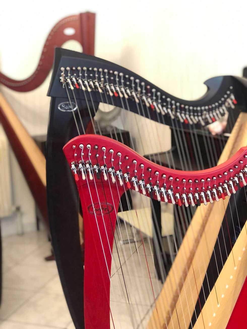 Gros plan artistique sur trois harpes Salvi acajou, rouges et noires, révélant la finesse des cordes et la précision de l’instrument. Illustration de l’univers musical de Stephanie Bernard, harpiste et compositrice.