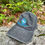 Thumbnail: Gray baseball cap featuring an embroidered logo of a white fish against a blue and green circle