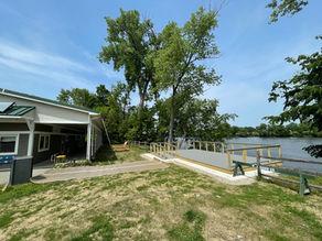 New viewing platform along the Connecticut River with trees and boathouse nearby.