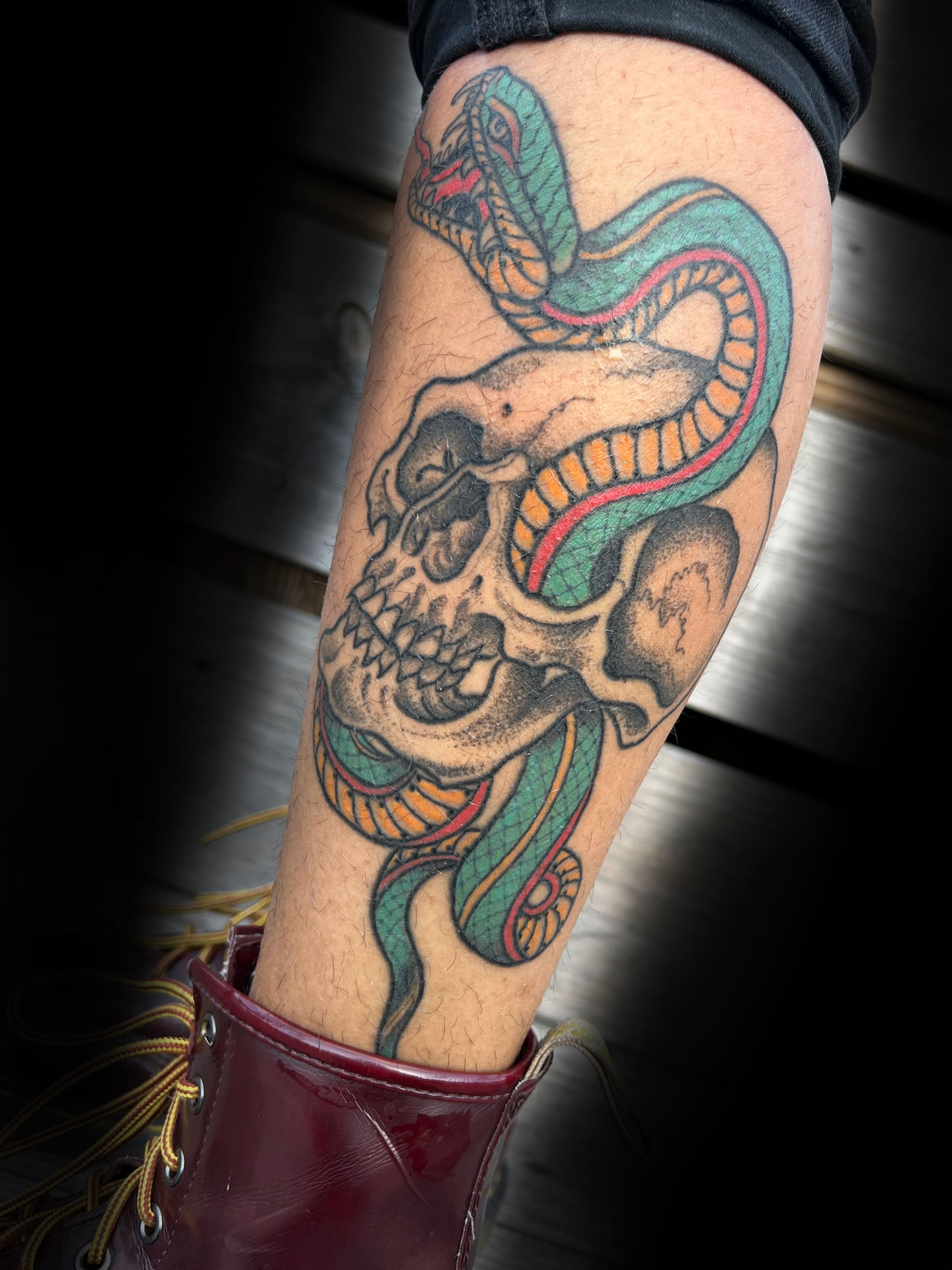 a person has a tattoo of a skull and snake on their leg