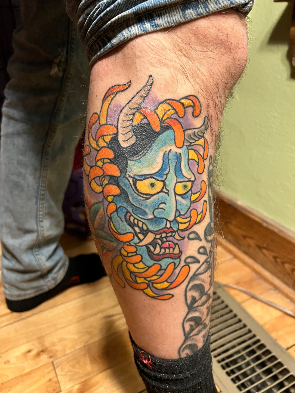 a person has a tattoo of a demon with horns on their leg