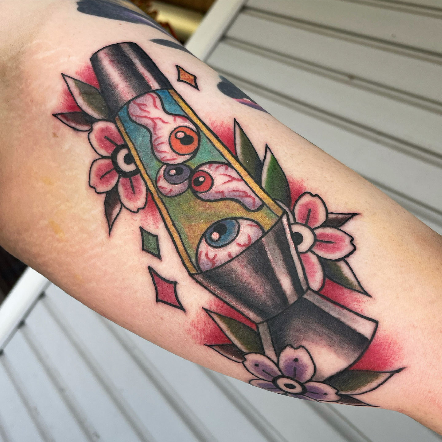 a tattoo of a lava lamp with eyes and flowers