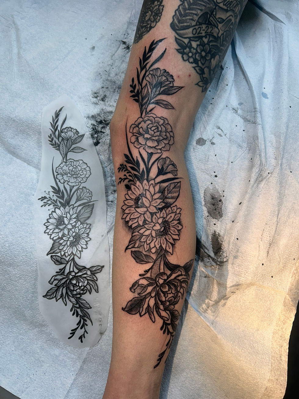 a black and white tattoo of flowers on a person 's arm