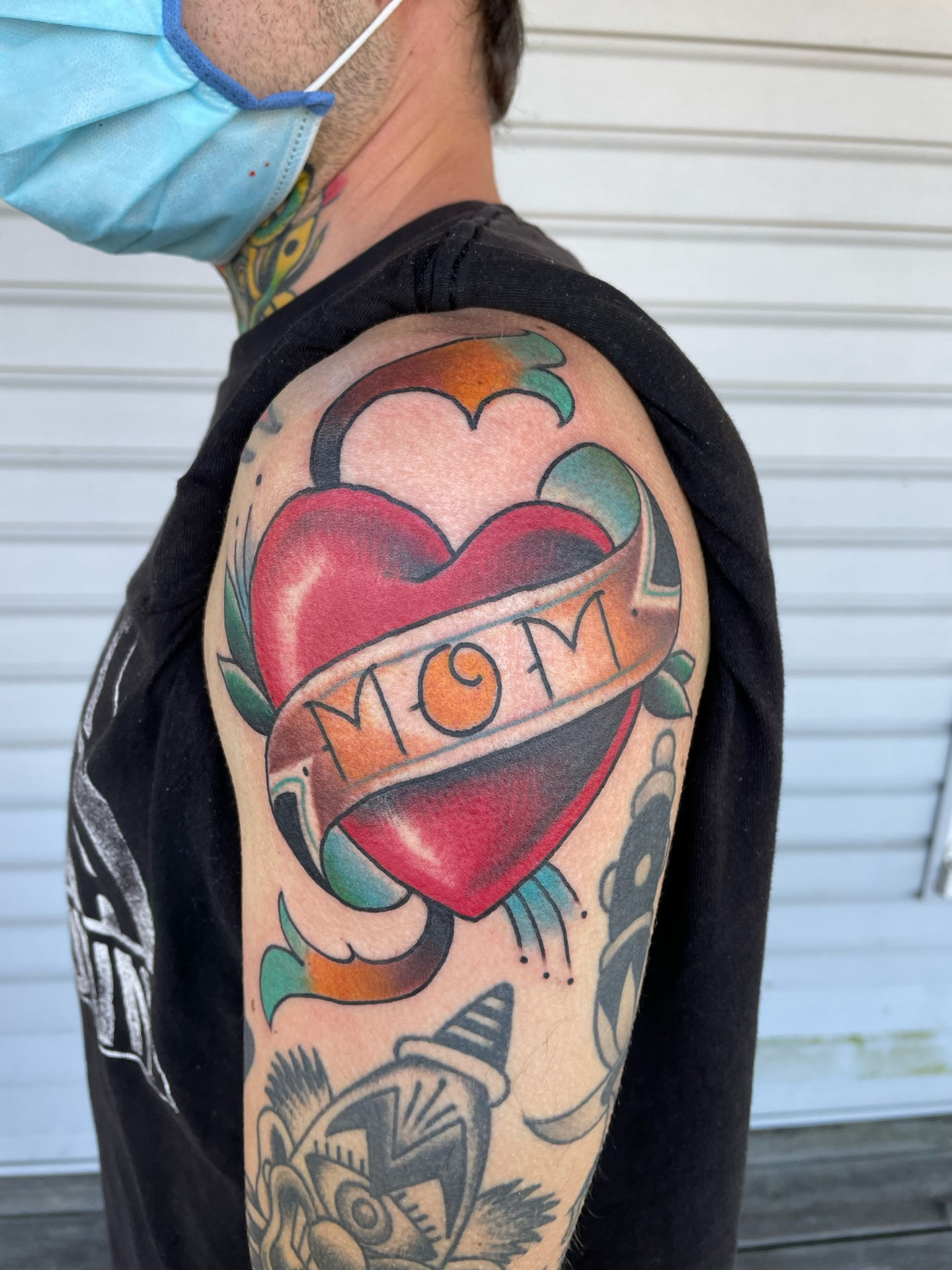 a man has a tattoo of a heart with the word mom on it