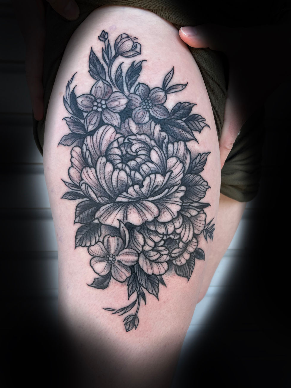 a black and white tattoo of flowers on a woman 's leg