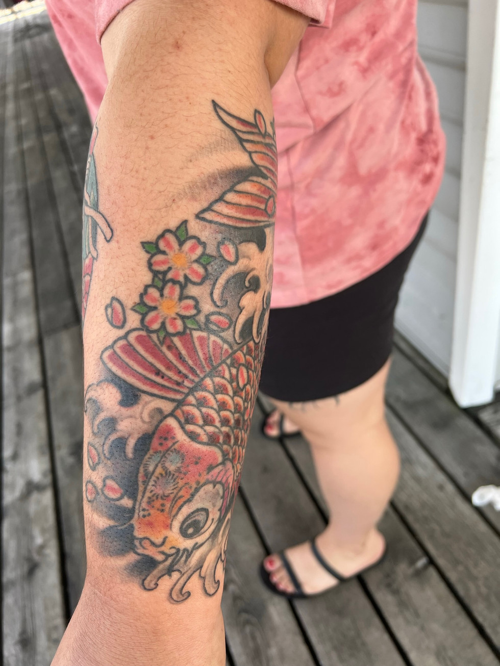 a woman has a tattoo of a fish and flowers on her arm