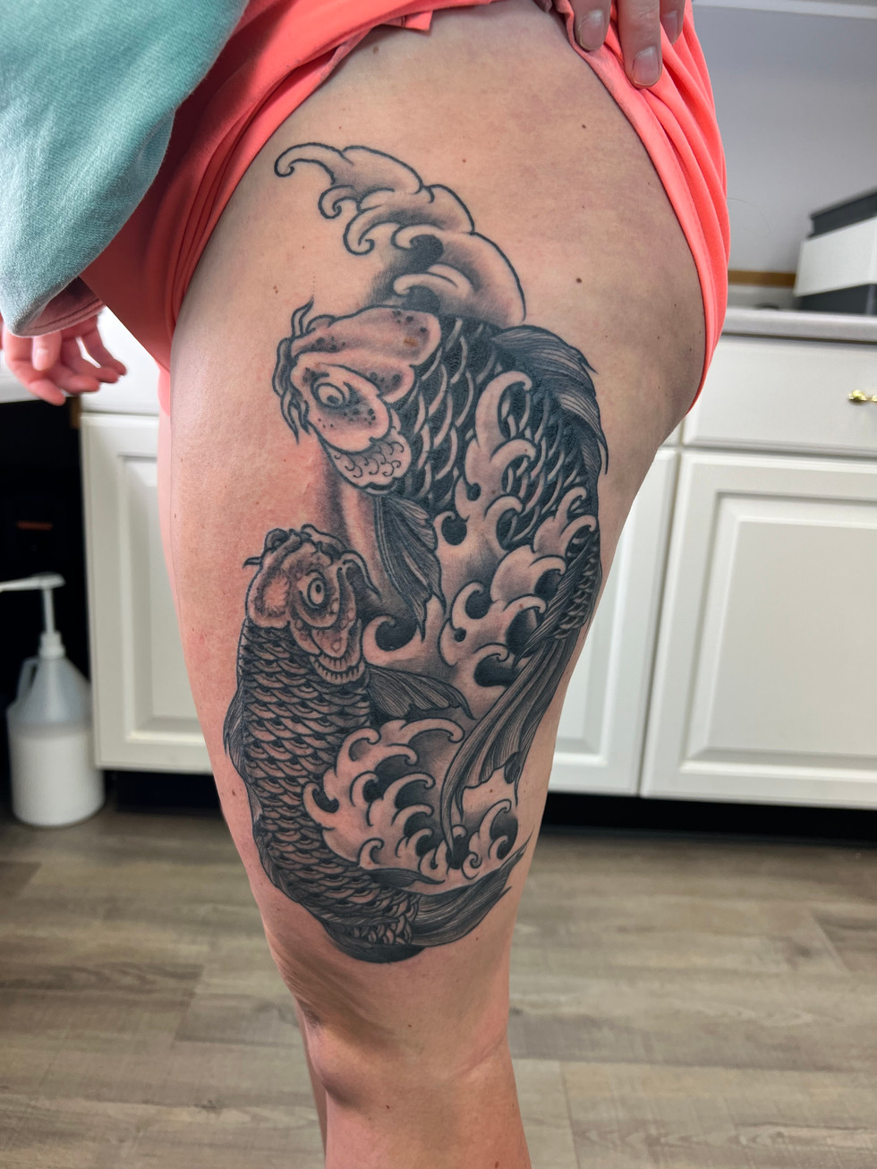 a woman has a tattoo of two fish on her leg