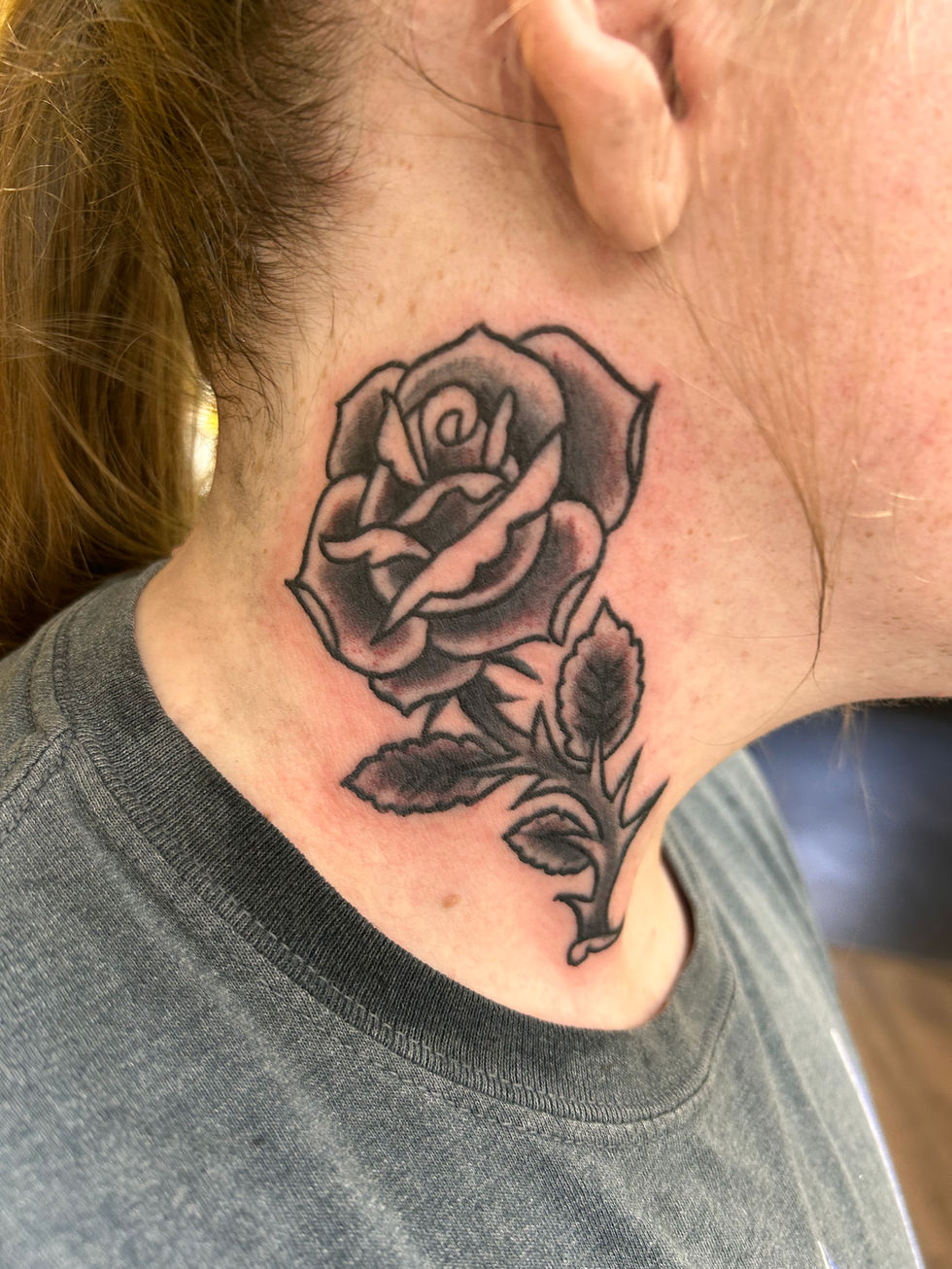 a woman has a tattoo of a rose on her neck