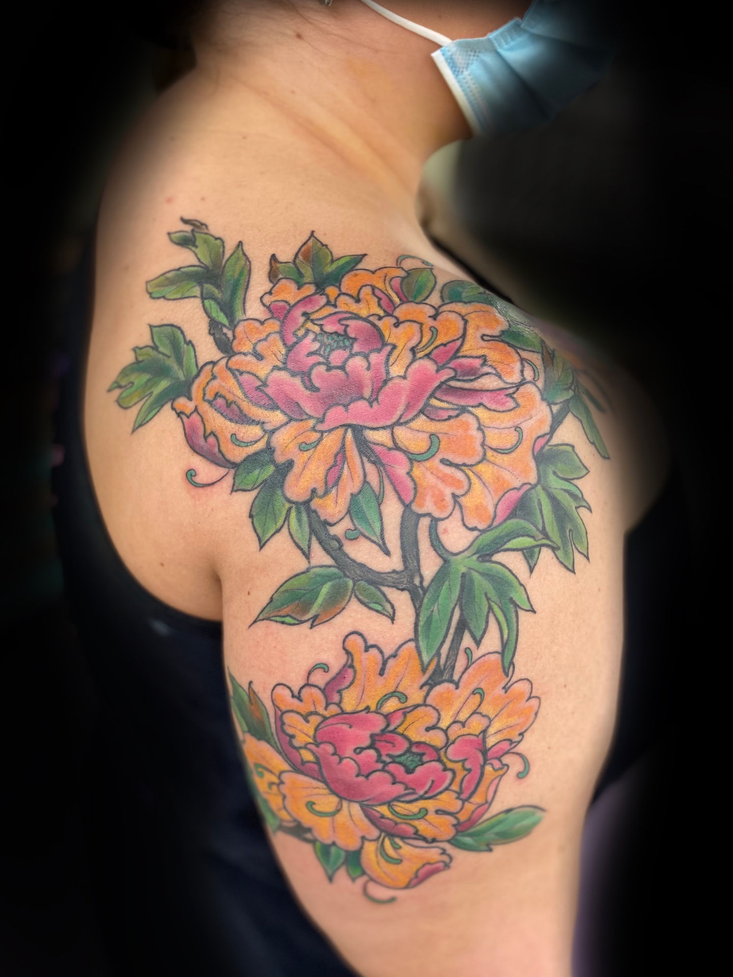 a woman has a tattoo of flowers on her shoulder
