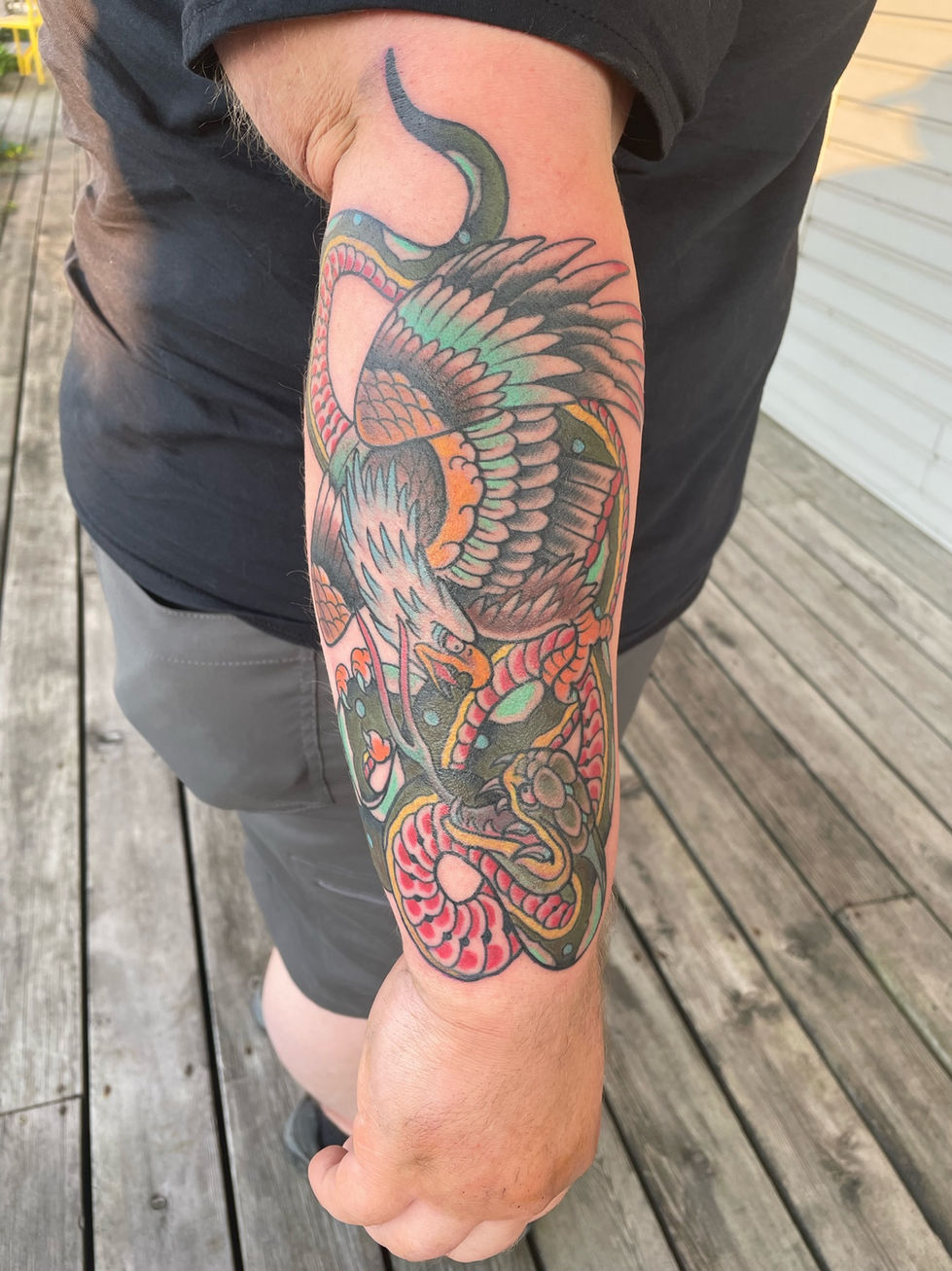a man has a tattoo of an eagle and snake on his arm